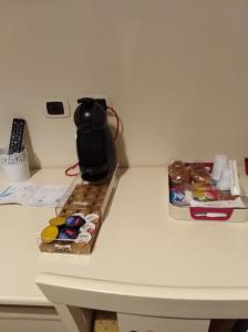 カノーザ・ディ・プーリアにあるDomuS al Corso B&Bのコーヒーポット付きテーブル、ドーナツ入りボックス