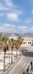 una calle con palmeras frente a un edificio en PENSION NAVAS en Cabo de Gata