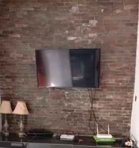 a flat screen tv hanging on a brick wall at Dee homes singaraja in Singaraja