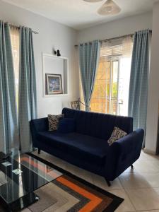 a blue couch in a living room with blue curtains at Vero Homes in Buwate