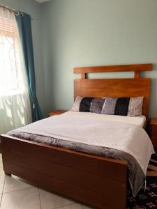 a bed with a wooden headboard in a bedroom at Vero Homes in Buwate