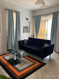 a living room with a blue couch and a glass table at Vero Homes in Buwate