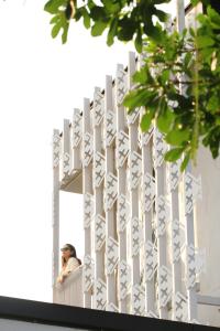 a man looking out of a white fence at Villa Mahaphrom in Nan