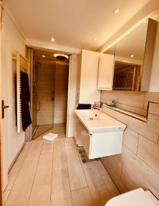 La salle de bains est pourvue d'un lavabo blanc et d'une douche. dans l'établissement Chalet JOLUKSI - mit Sprudelbad, à Grindelwald