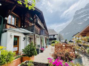 une maison avec des chaises et des fleurs devant elle dans l'établissement Chalet JOLUKSI - mit Sprudelbad, à Grindelwald