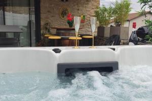 a hot tub with two wine glasses and a fireplace at Jacuzzi au Lemon Tree et charme des pierres dorées in Panossas