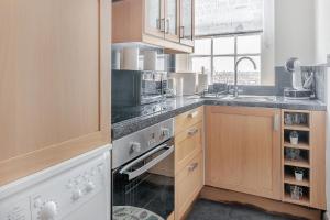 uma cozinha com armários de madeira e um forno com placa de fogão em Stunning Flat Next To Hyde Park em Londres