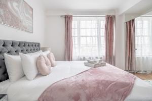 um quarto com uma cama grande e um cobertor rosa em Stunning Flat Next To Hyde Park em Londres