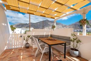 una mesa y sillas en un balcón con montañas al fondo en DP Homes Santorini, en Perissa
