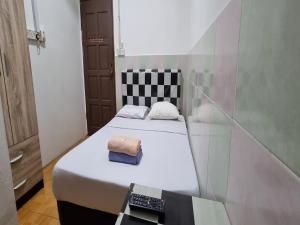 a small room with a bed and a remote control at OYO 90972 Jj Homestay in Miri