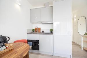 a kitchen with white cabinets and a wooden table at Dandi Northolt Road in Harrow in Harrow