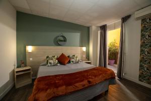 マントンにあるホテル パリジャンのベッドルーム1室(大型ベッド1台、オレンジ色の枕付)