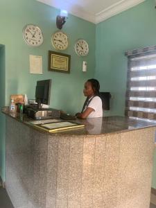 a woman sitting at a counter with clocks on the wall at THE GROOVE GUEST HOUSE in Lagos