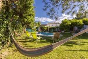 a hammock in a yard with chairs and a pool at Suite Zen Grand Lit in Pierrelatte