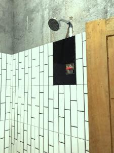 a shower in a bathroom with white tile on the wall at Melody Surf Camp - Ekas Lombok in Ekas