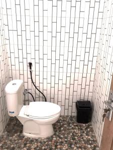 a bathroom with a toilet in a white tiled wall at Melody Surf Camp - Ekas Lombok in Ekas