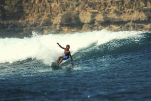 a man riding a wave on a surfboard in the ocean at Melody Surf Camp - Ekas Lombok in Ekas