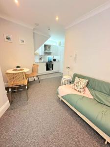 een woonkamer met een groene bank en een tafel bij Bournemouth Beach Apartment in Bournemouth