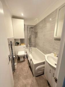 een badkamer met een toilet, een bad en een wastafel bij Bournemouth Beach Apartment in Bournemouth