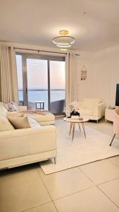 a living room with white furniture and a view of the ocean at Luxury Ocean Front Apartment in Ras al Khaimah