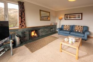 a living room with a fireplace and a blue couch at Lang Parrock, Little Langdale in Little Langdale