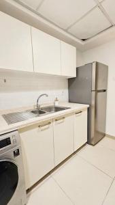 a white kitchen with a sink and a refrigerator at Luxury Ocean Front Apartment in Ras al Khaimah