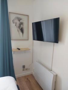 LonsにあるStudio de charme - Idéal Couple & Pro - Calmeの壁にテレビが付いた客室で、ベッドが備わります。