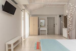 a white room with a bed and a tv on a wall at Zefyros Sea View Hotel in Platamonas