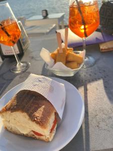ein Sandwich und Pommes auf einem Teller auf einem Tisch mit Getränken in der Unterkunft AG SUITE TRAPANI in Trapani
