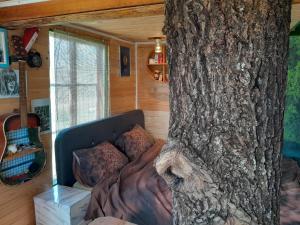 uma cama num quarto ao lado de uma árvore em Tree house Ramona & Fairytale wooden house by Ljubljana em Grosuplje