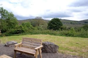 un banco de madera sentado en la parte superior de un campo en Haytor Rocks, Dartmoor escape en Bovey Tracey