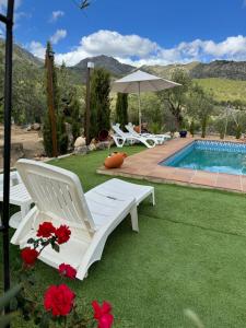 una silla blanca reclinable junto a una piscina en Villa El Pedregal - Parque Sierra de las Nieves, en Yunquera