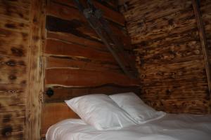 a bed in a wooden room with white pillows at Lodges des Grands Chênes in Andelarrot