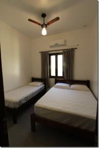 1 dormitorio con 2 camas y ventilador de techo en Velas Chalés, en Ubatuba