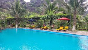 a pool at a resort with chairs and umbrellas at Fairy Mountain Retreat in Ninh Binh