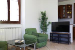 sala de estar con silla verde y TV en Villa Belveder - Piscina esclusiva, Parco e Panorama, en Castelraimondo