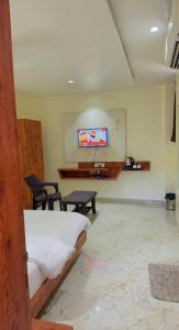 a bedroom with a bed and a desk and a tv at Hotel Apex, Akkalkot in Akalkot