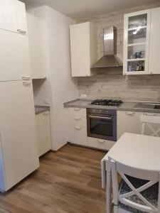 uma cozinha com armários brancos, um fogão e uma mesa em Sweet Home Francesco & Chiara em Chioggia