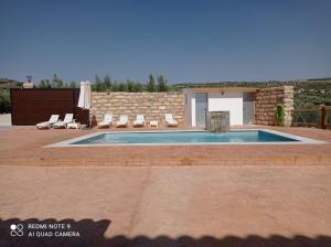 a swimming pool in a patio with chairs and a building at El Bujeo Montefrio in Montefrío
