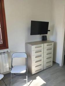 uma cadeira e uma televisão em cima de uma cómoda em Sweet Home Francesco & Chiara em Chioggia