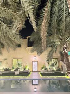 a house with palm trees and a swimming pool at Glory Resort in Al Ahsa