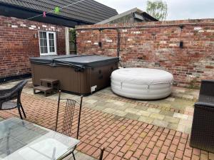 a hot tub sitting on a brick patio with a table and a table at The Little Hexthorpe house in Doncaster