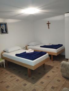 two beds in a room with a cross on the wall at Family guesthouse in forest Ana & Stjepan Nikolić in Međugorje