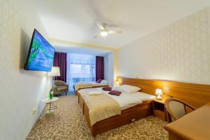 um quarto de hotel com duas camas e uma televisão de ecrã plano em Kontakt Wellness Hotel em Stará Lesná