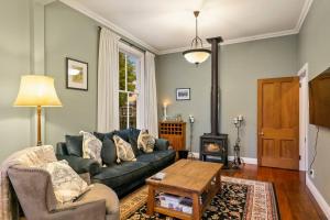 un salon avec un canapé et une cheminée dans l'établissement Historic Charm in Greytown - Tranquil setting - walk to town, à Greytown
