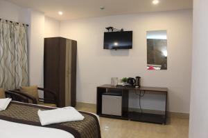 um quarto de hotel com uma cama e uma televisão na parede em Hotel Rhishabh em Aberdeen
