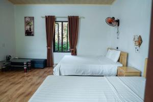 a hotel room with two beds and a window at Tran Chau Garden Home in Cat Ba