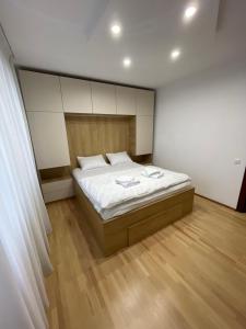 スチャヴァにあるCentral Cozy Apartament Near Monasteryのウッドフロアのベッドルーム1室(白いシーツ付きのベッド1台付)