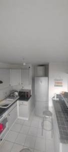 - une cuisine blanche avec un réfrigérateur et un tabouret dans l'établissement Chambre dans Appartement - Grenoble, France à 8 min du centre-ville, à Grenoble