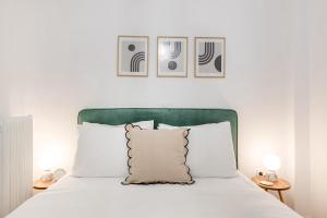 Sunny 2BR Apartment in Nea Smyrni by UPSTREET في أثينا: سرير مع اللوح الأمامي الأخضر والوسائد البيضاء